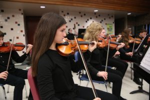 Middle school students play violins