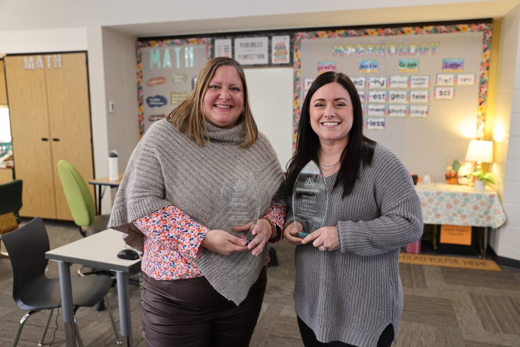 two women smiling, each holding an award