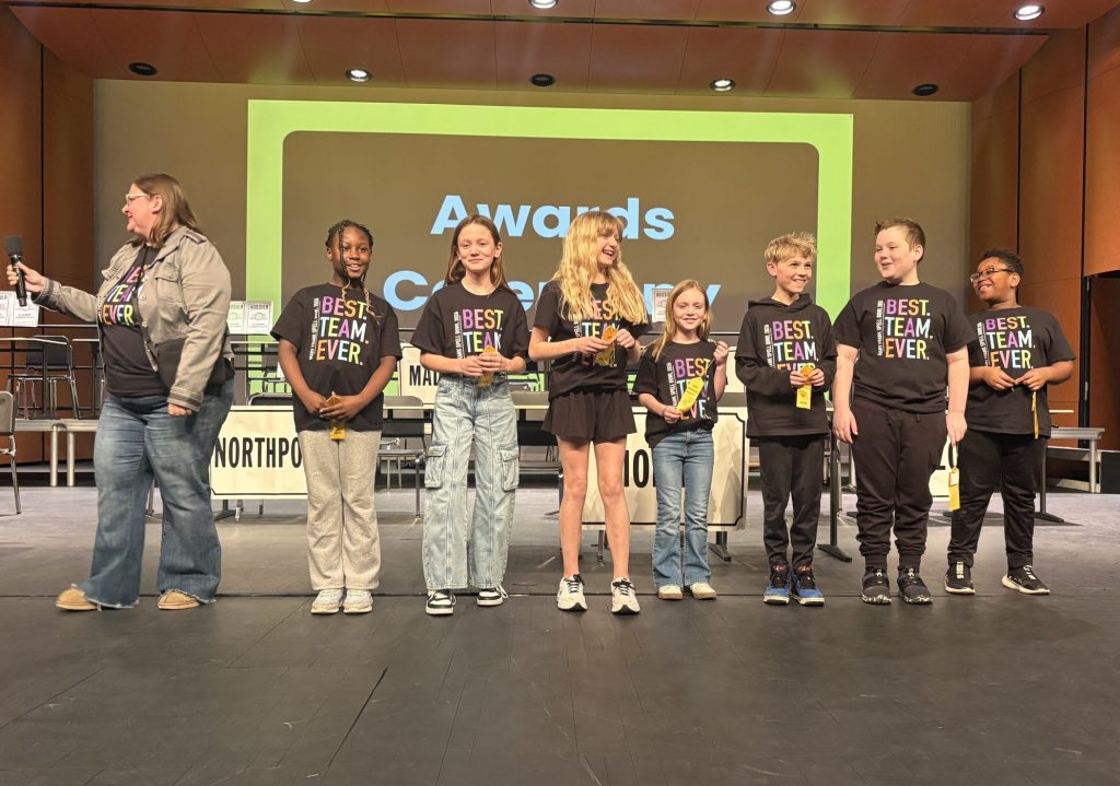 People standing on stage at an awards ceremony, posing for a group photo.