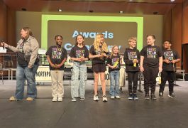People standing on stage at an awards ceremony, posing for a group photo.