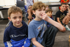Two boys sitting on floor in classroom.