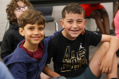 Two young boys posing for a photo in front of a classroom setting.