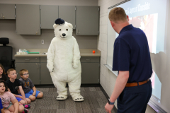 Man in front of a class with a large white teddy bear costume.